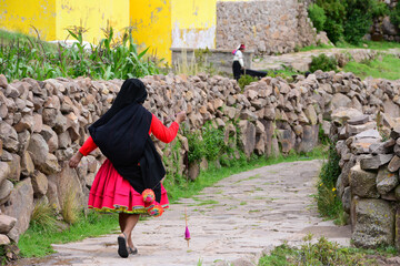 woman walking wearing  traditional dress in Taquile island, Lake Titicaca, Peru