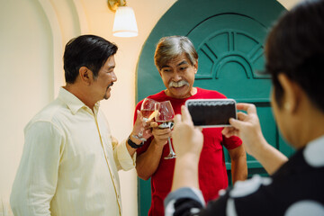 Senior people celebrate with wine glass and take a photo with smartphone.