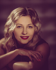 Fototapeta premium Portrait of beautiful young blonde with curly shiny hair and red lips. image toned in warm colors in retro style