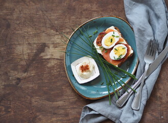 Open sandwich with dark rye bread with cheese, salmon fish on a wooden background.Healthy natural breakfast.