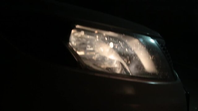 Glowing headlight of a car driving at night. Fast forward movement, fog can be encountered. On a black background. In the dark.