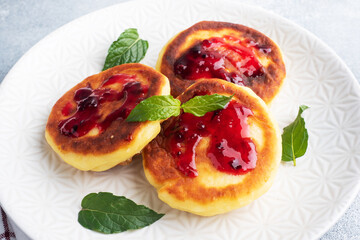 Fritters of cottage cheese with blueberries jam. Cheese curd cheesecakes, pancakes on a grey concrete background