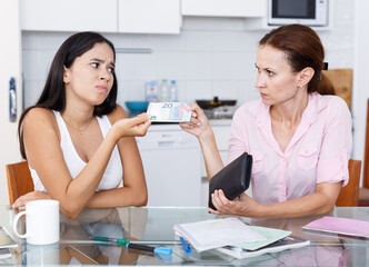 Teenage girl asks her mother some cash in kitchen