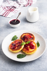 Fritters of cottage cheese with blueberries jam. Cheese curd cheesecakes, pancakes on a grey concrete background. Copy space.