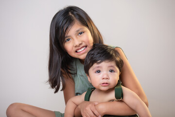 Mexican siblings  girl and  baby boy  isolated smiling wearing green clothes