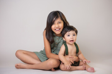 Mexican siblings  girl and  baby boy  isolated smiling wearing green clothes