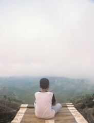 Fototapeta na wymiar A boy enjoy the view and fog in the morning at top hill