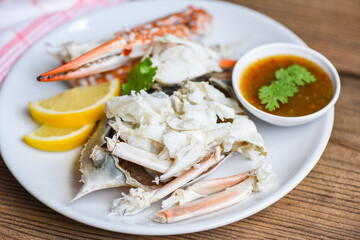 Crab meat - Cooked crab claws and legs on white plate and seafood sauce on the table , blue swimming crab