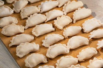 Fototapeta na wymiar frozen dumplings handmade lying in rows on wooden board