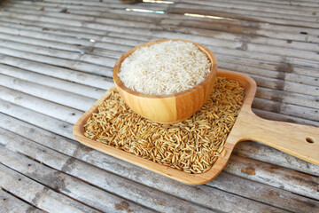 White rice (Thai Jasmine rice) on wooden bowl and wooden plate Put on a bamboo table