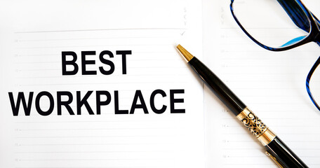 In the notebook is the text BEST WORKPLACE, next to the pen and glasses.