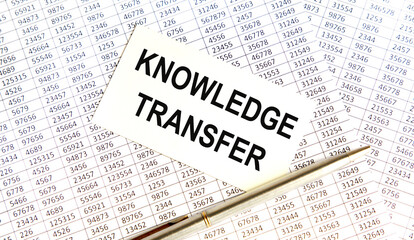 Obraz premium On the background of the reporting is a business card with the inscription KNOWLEDGE TRANSFER, next to the pen.