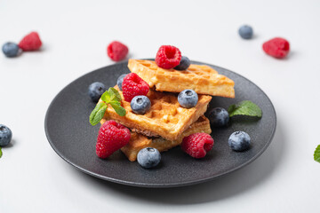 Belgian waffles with raspberries, blueberries and mint. Delicious breakfast