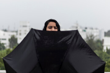 portrait of woman with black umbrella, covering face, selective focus