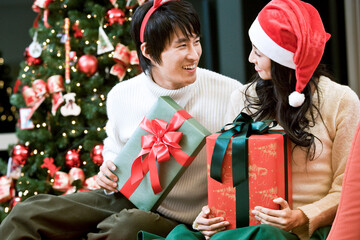 young man and woman with the Christmas tree and gift boxes
