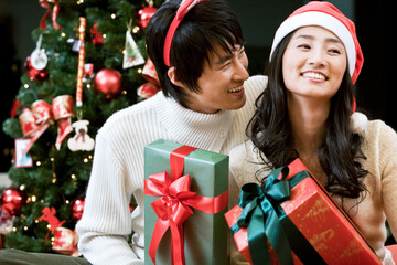 young man and woman with the Christmas tree and gift boxes