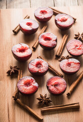 Sliced red plums with cinnamon sticks and anise stars on the wooden table. Selective focus. Shallow depth of field. 