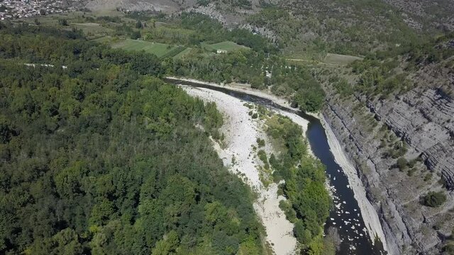 Lazy Ardeche River flows below high stone cliffs near Aubenas, France