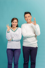 Beautiful, attractive, sexy smiling couple gesturing ok sign over blue background