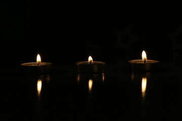 three candles are burning on a dark background. High quality photo