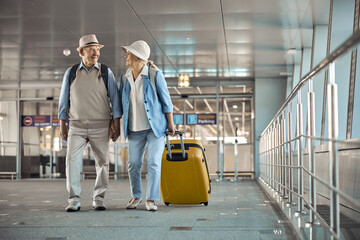 Two happy senior travelers walking hand in hand