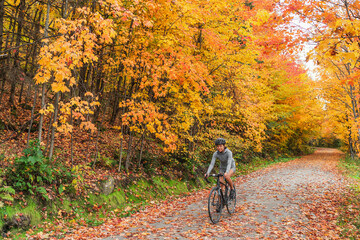 Autumn biking happy woman traveling on road bike through foliage path in nature forest outdoors....