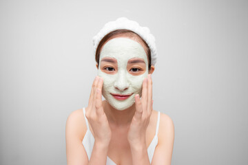 Portrait of young Asian girl with clay mask over white background.