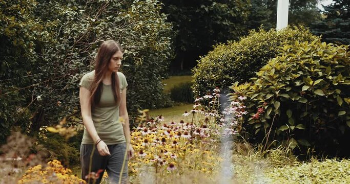 Young woman walking through beautiful garden alone with foreground elements.