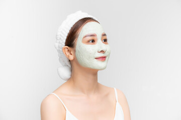 Portrait of beautiful young Asian woman with clay mask and towel on her hear over white background.