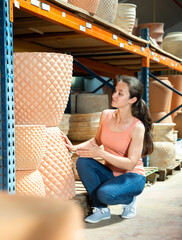 Obraz premium Female seller is standing near clay pots in stock. High quality photo