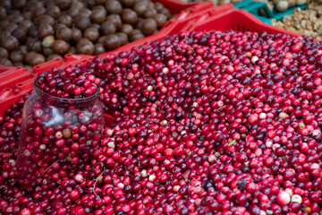 Red fresh healthy cranberries and lingonberries in a street food market ready for selling and eat, with glass jar 