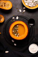 pumpkin puree soup in pumpkin with seeds and sesame seeds on a black board