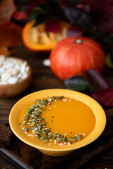 pumpkin cream soup with seeds and sesame seeds in a yellow plate