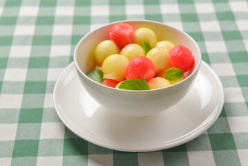 Watermelon granita ice cream. Melon and watermelon sorbet ice cream balls in a white bowl over green plaid table cloth.