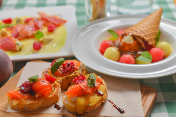 Delicious fruit salmon bruschetta with sauce served on a wooden board over green plaid table cloth.