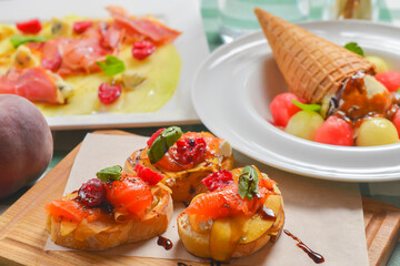 Delicious fruit salmon bruschetta with sauce served on a wooden board over green plaid table cloth.