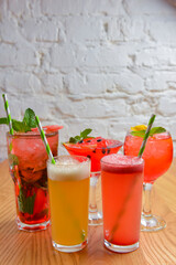 Summer cocktails and soft drinks with pieces of fruit on wooden table. Refreshing summer beverage for hot weather.