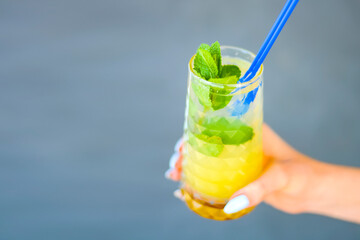 Summer cocktail and soft drink with pieces of fruit in a hand. Refreshing summer beverage for hot weather.