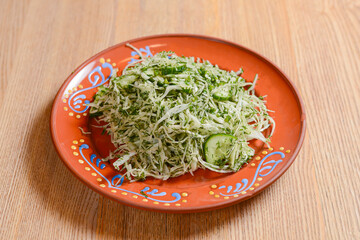 A plate of cabbage and cucumber salad. Cole salad over the wooden table background.
