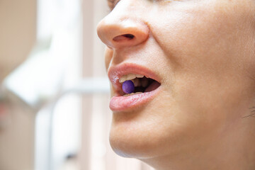 Woman taking purple disclosing tablet for plaque indication