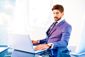 Businessman using laptop in the office while sitting at office desk