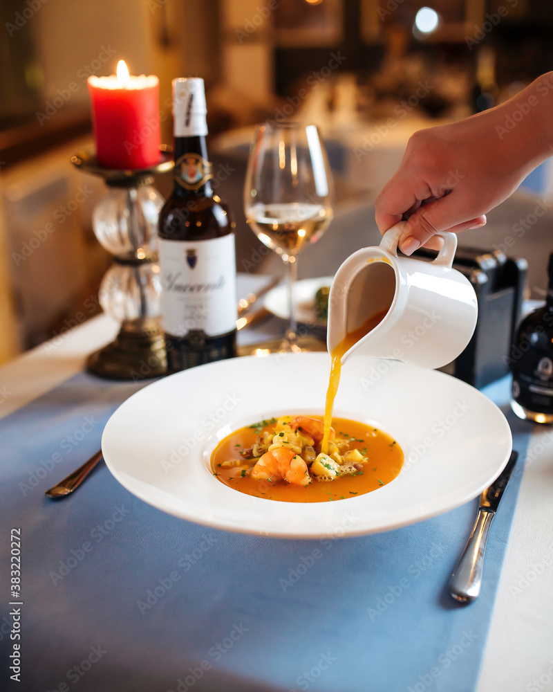 Wall mural Pouring broth in a plate with seafood soup  - Wall murals