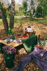 Outdoor Gender Reveal Party Decorations. girl or boy. beautiful photo zone with cake and fruits.
autumn decor with purple and green color. Two glasses of the red wine and tasty food and accessories 