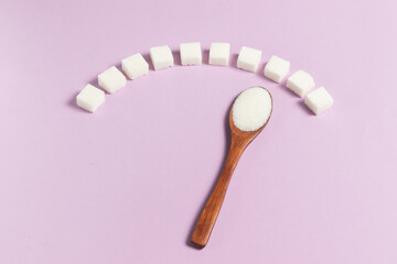 Blood sugar scale made from white sugar cubes and wooden eco spoon on light background