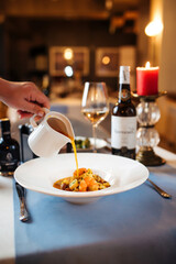 Pouring broth in a plate with seafood soup 