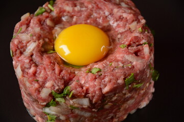 Beef tartare with raw egg,  and onions, fresh herbs. French cuisine