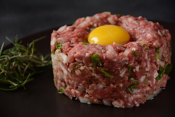 Beef tartare with raw egg,  and onions, fresh herbs. French cuisine