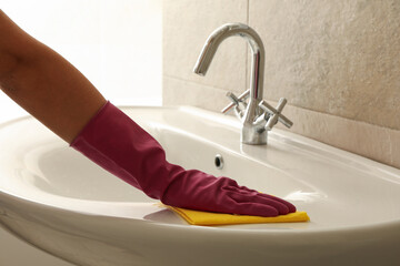 Woman in rubber pink glove cleaning sink