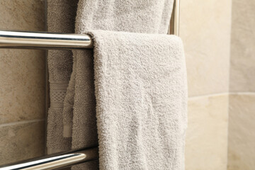 Modern heated towel rail on tiled bathroom wall