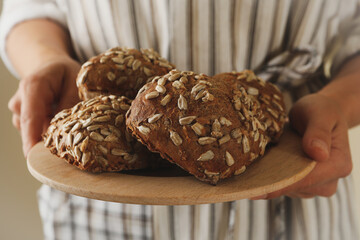 Woman hold fresh baked buns with sunflower seeds